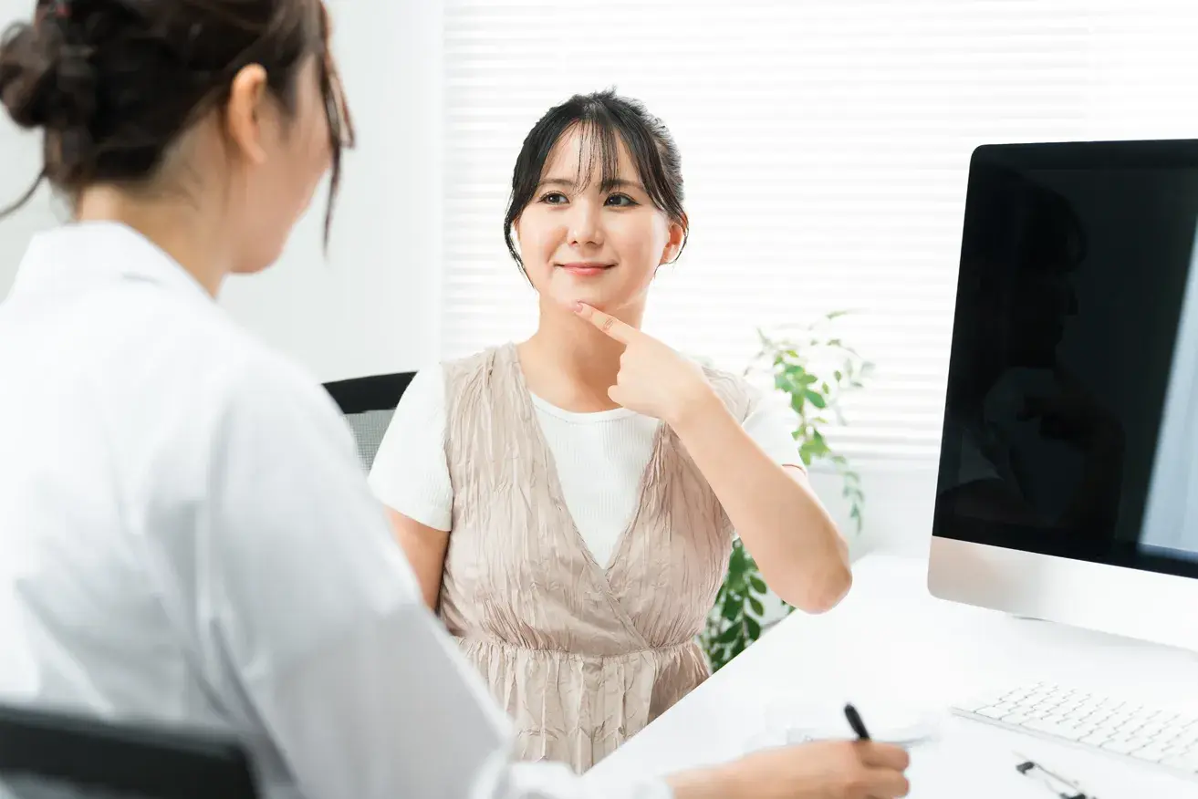 Woman pointing at her chin during a plastic surgery consultation