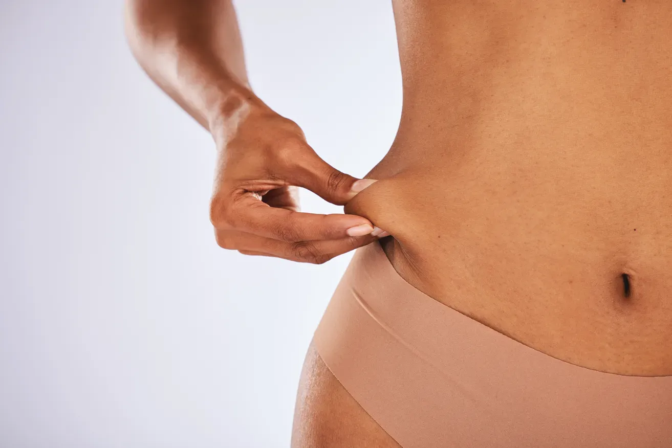 Woman holding onto loose skin on her abdomen