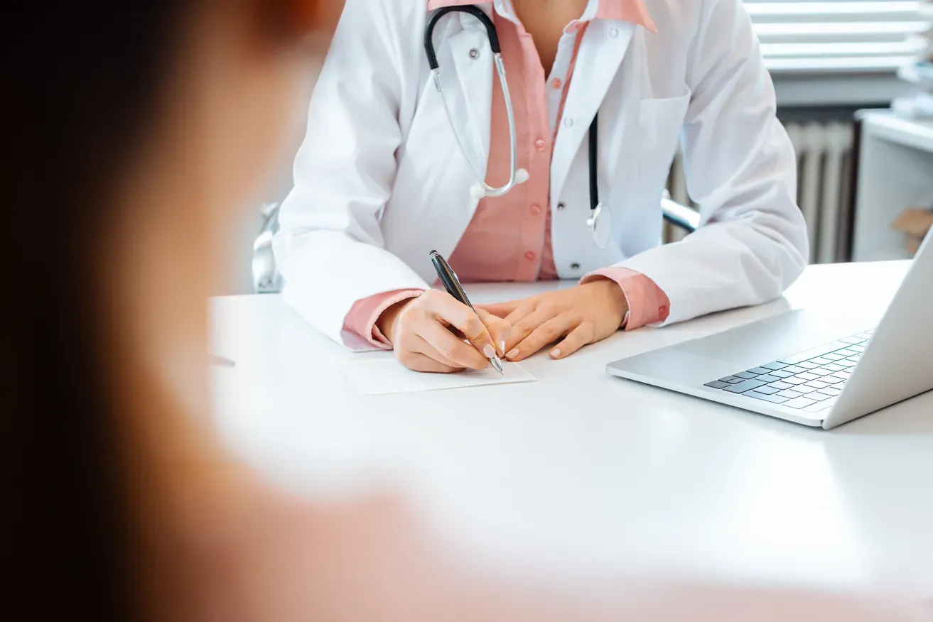 Plastic surgeon noting down patient’s concerns during consultation
