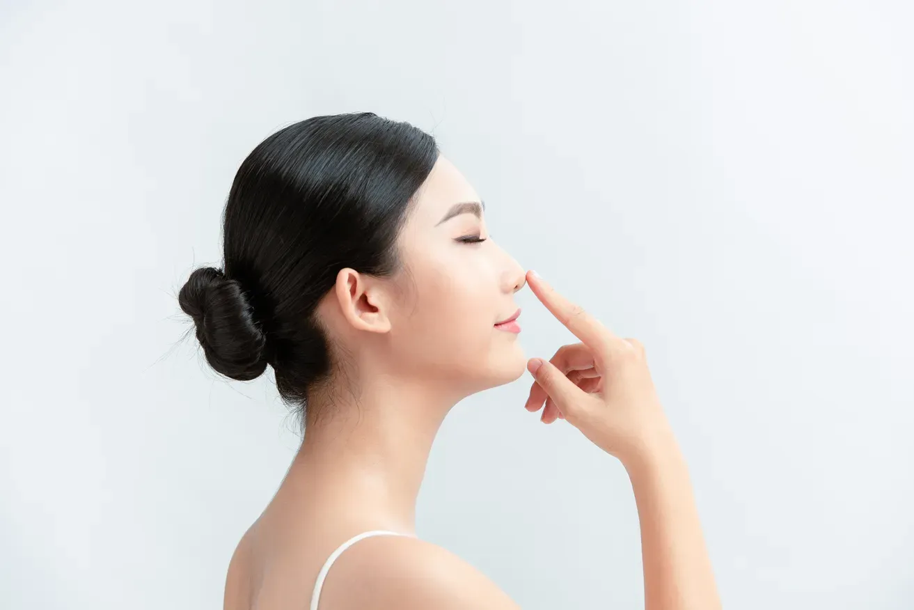 Side profile of woman pointing at her nose