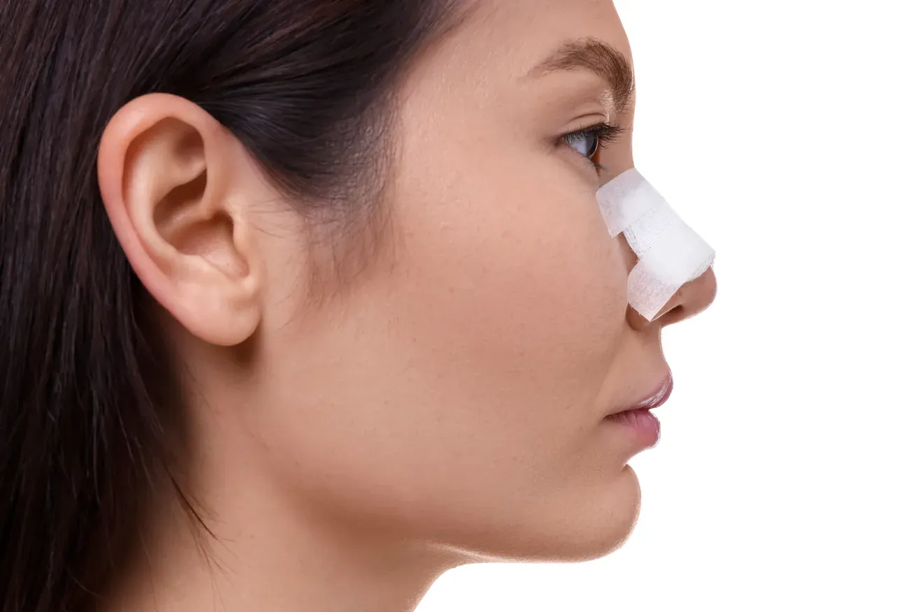 Woman with a protective bandage on her nose during recovery after plastic surgery