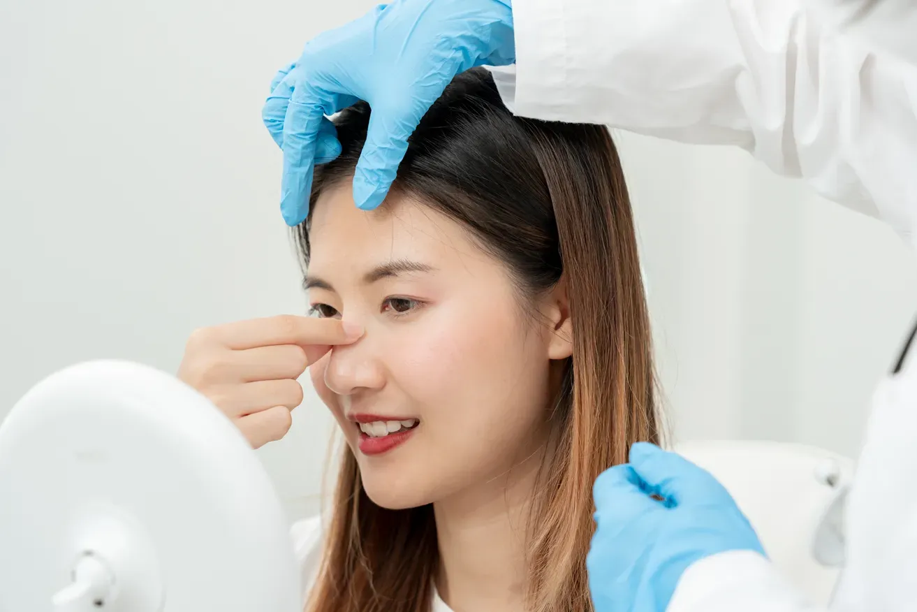 Plastic surgeon inspecting woman’s nose for rhinoplasty