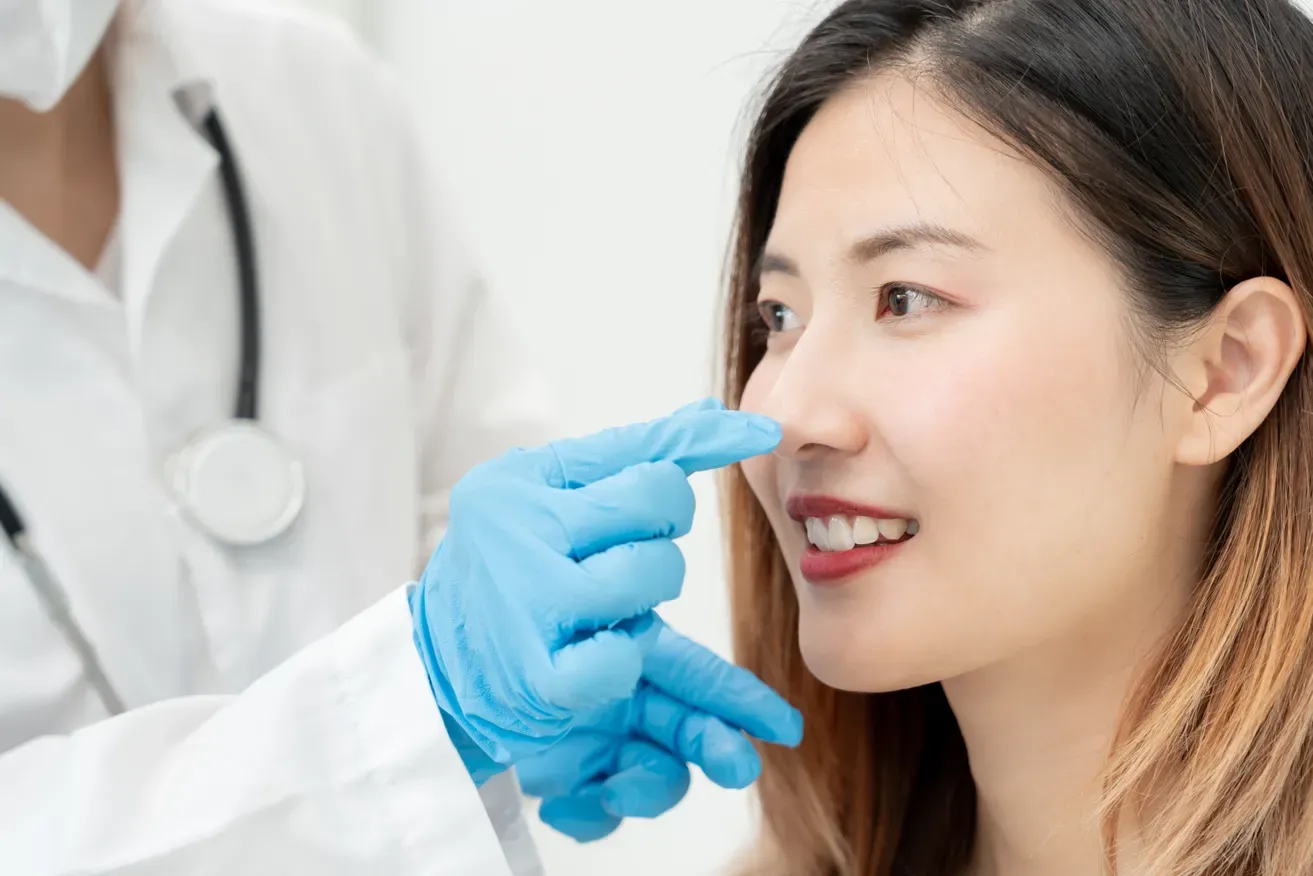 Plastic surgeon examining woman’s nose during a rhinoplasty consultation