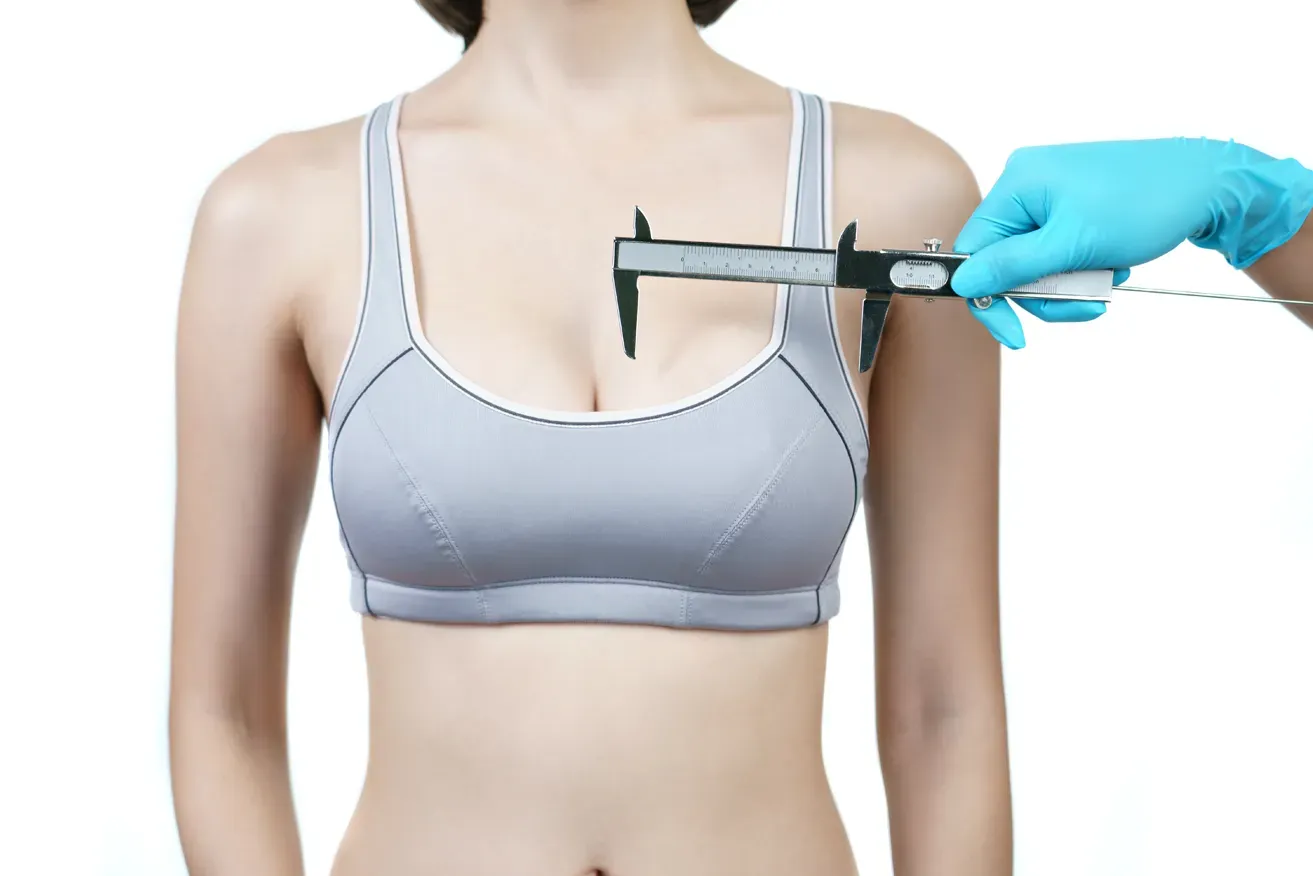 Plastic surgeon measuring woman’s breast for breast reduction