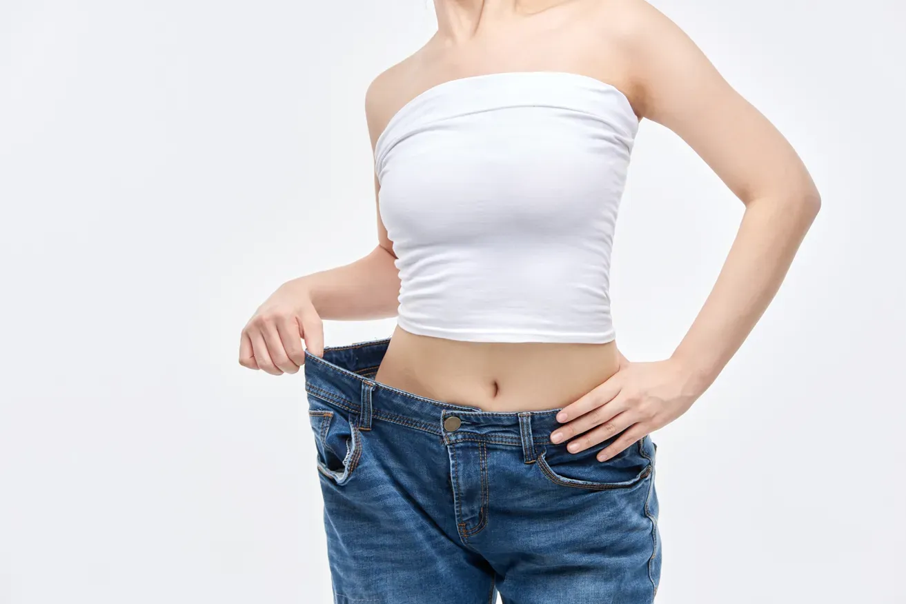 Woman in loose jeans after effective liposuction