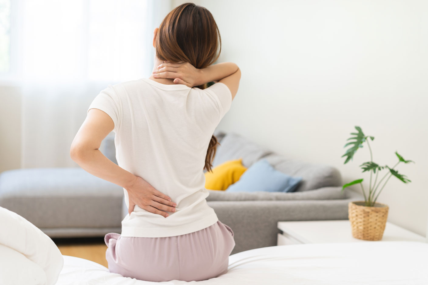 Woman holding her neck and lower back experiencing discomfort.