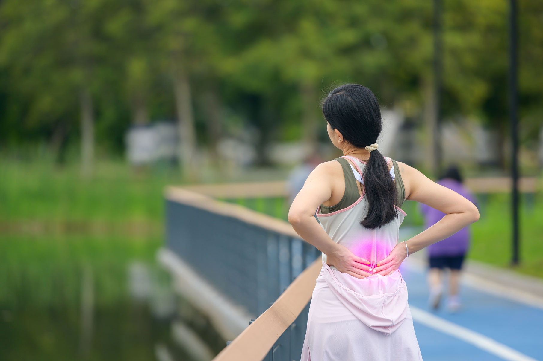 Woman experiencing back discomfort during exercise and holding her lower back during a workout.