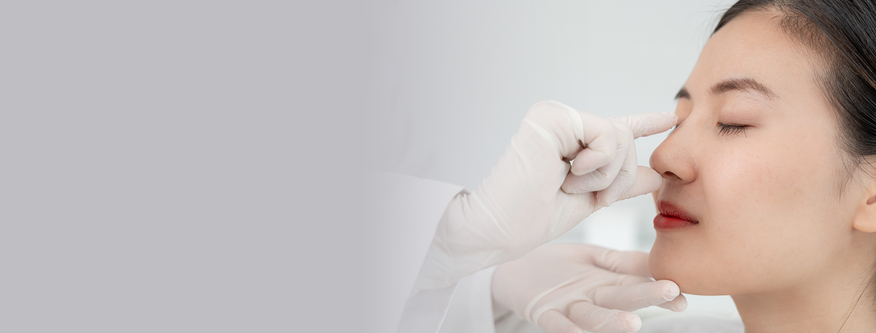 Surgeon assessing a woman’s nose during a revision rhinoplasty consultation.