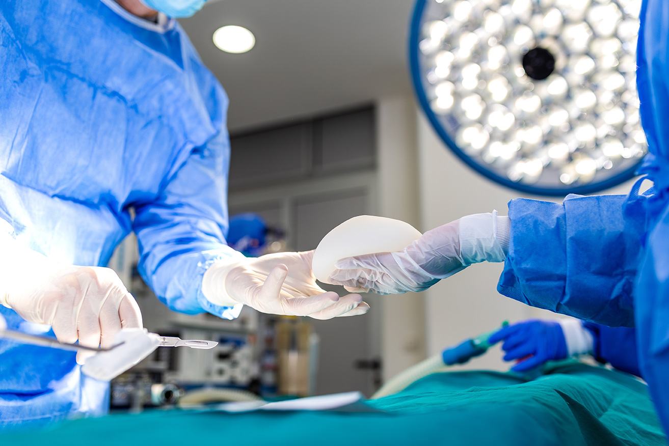 Plastic surgeon performing breast surgery in an operating theatre.