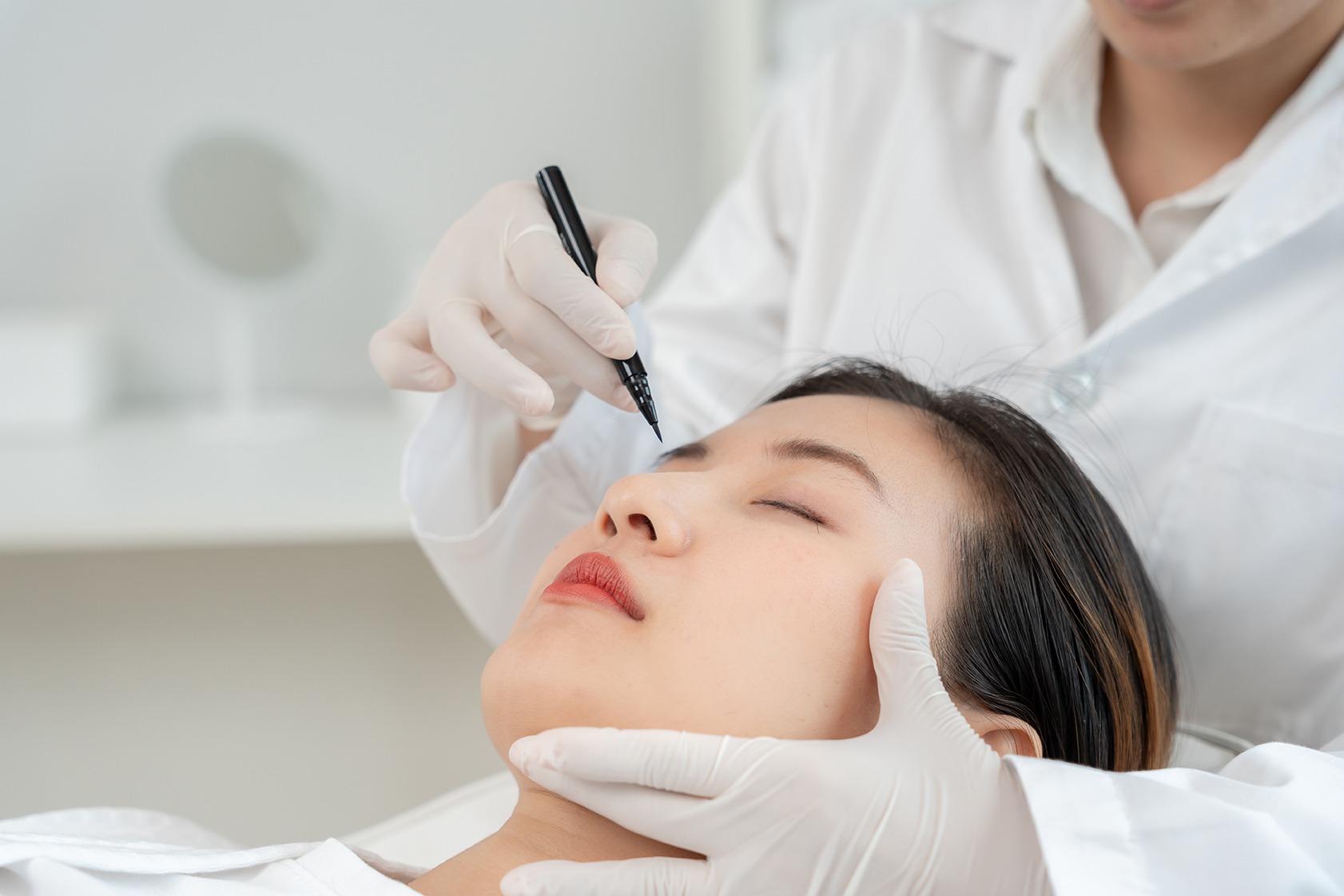Woman undergoing facial assessment with a plastic surgeon for revision rhinoplasty.